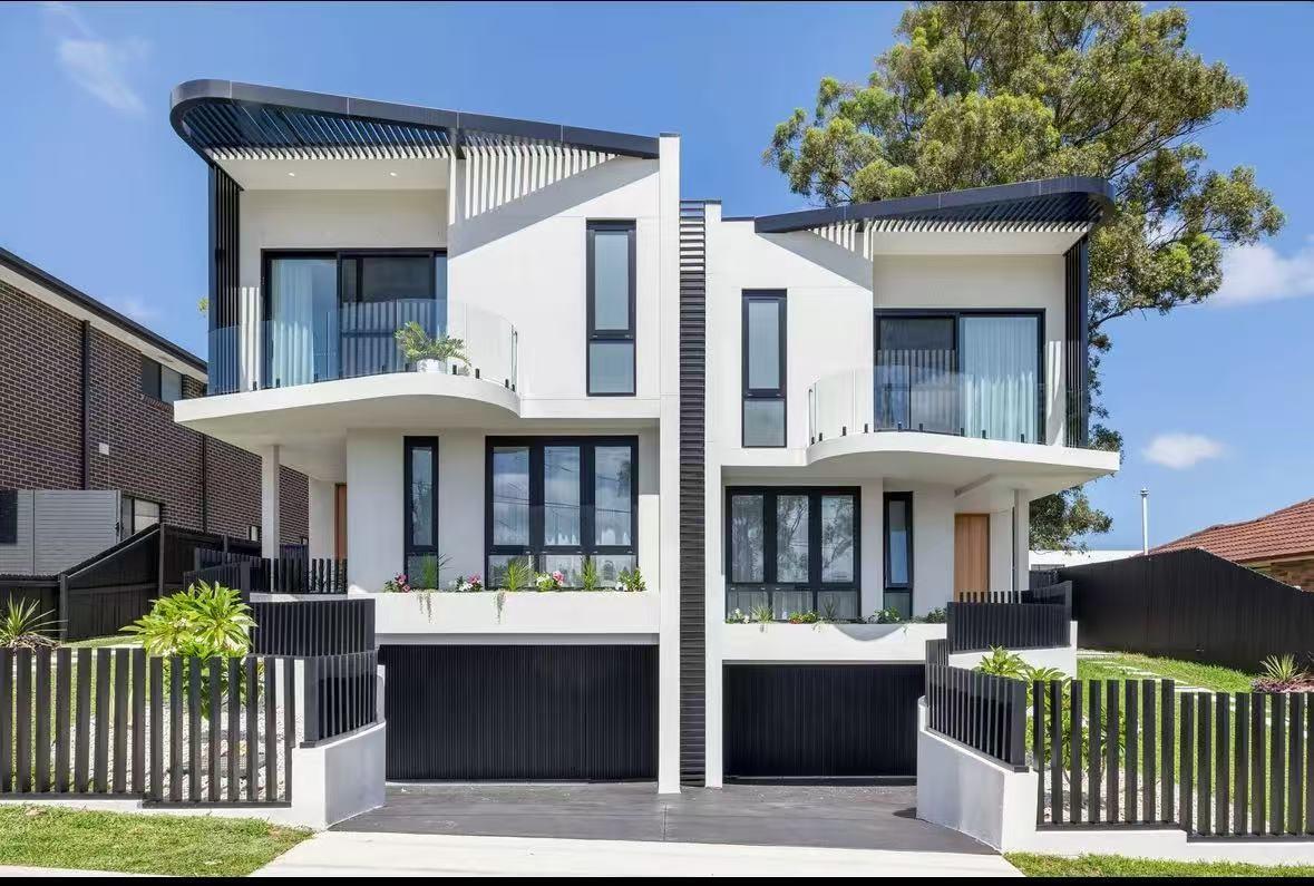 Two-storey rendered duplex with black-framed aluminium glazing, completed and landscaped
